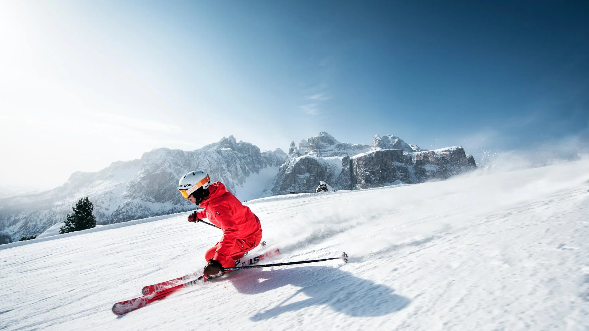 A skier making turns on a sunny Dolomite piste