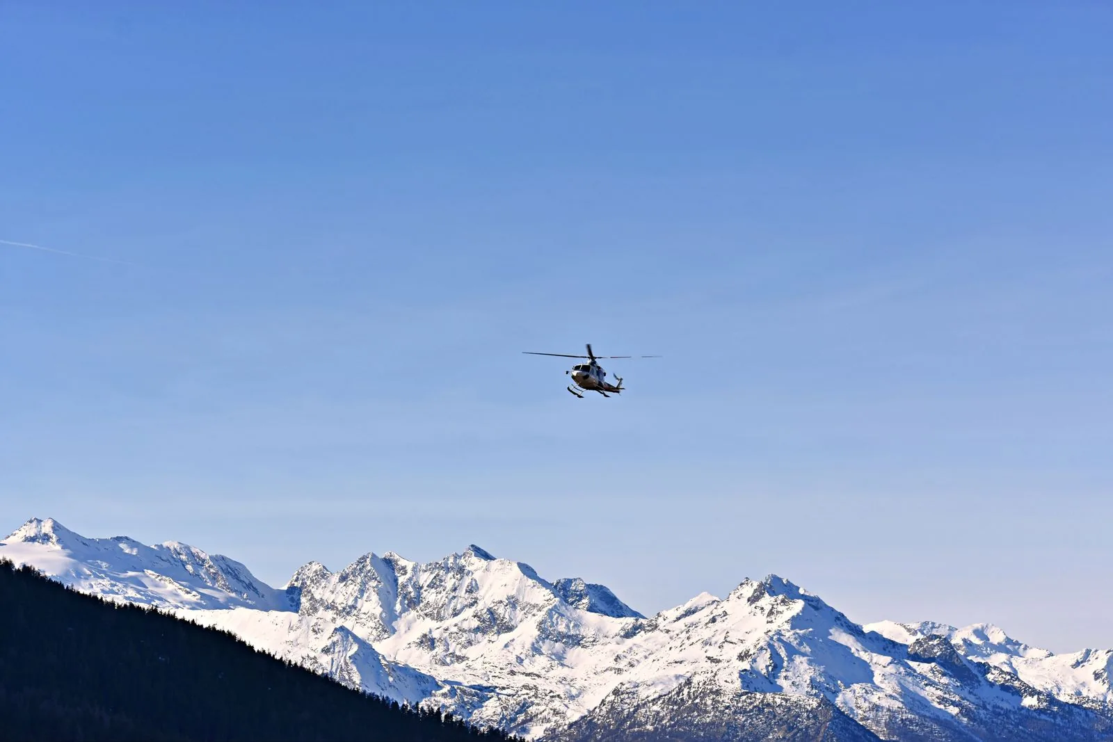 A helicopter above snowy mountains